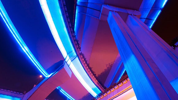 Il s'agit d'achitecture. La photo est prise en contre-plongée. On voit des piliers. L'éclairage est bleu et intense. 