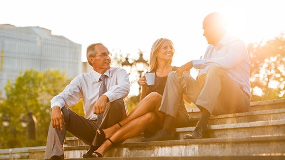 Trois personnes qui discutent assises sur des marches dehors au soleil Trois personnes qui discutent assises sur des marches dehors au soleil