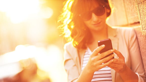 Femme dehors au soleil sur son téléphone Femme dehors au soleil sur son téléphone