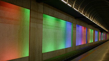 Photo d'architecture. C'est un tunnel sous-terrain, dans le métro, avec des rectangles sur le mur, lumineux et multicolors qui sont de plus en plus petits car de plus en plus éloignés.