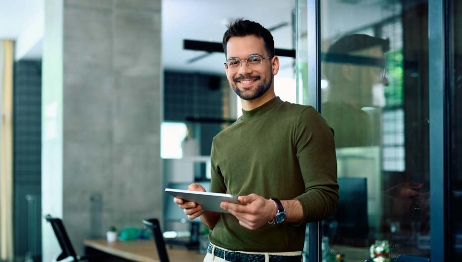 Happy entrepreneur using digital tablet in office and looking at