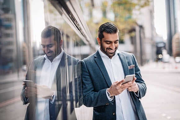 Indian businessman using mobile app on smart phone to do the e-banking and money transaction to other checking account in India.