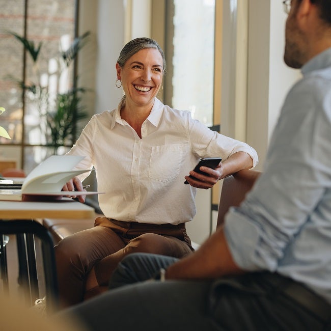 Woman talking with coworker at office desk. Businesswoman having discussion with team member in office.